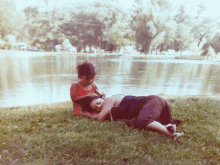 a woman is laying on the grass next to a child