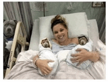 a woman is laying in a hospital bed holding two newborn babies .