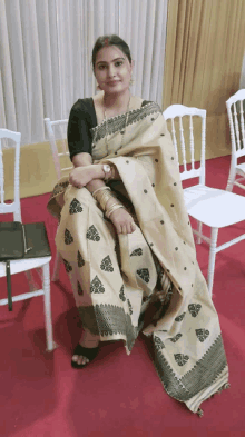 a woman in a saree sits on a red carpet