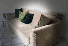 a beige couch with green and black pillows