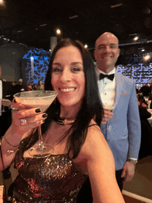 a woman in a sequined dress is holding a martini glass while standing next to a man in a tuxedo