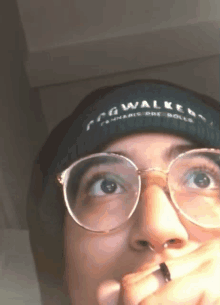 a person wearing glasses and a beanie that says fog walker