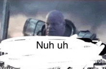 a bald man is sitting in the driver 's seat of a car with the words `` nuh uh '' written above him .