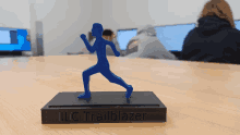 a blue statue of a person is on a wooden table and says llc trailblazer