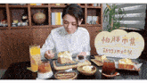 a woman sits at a table with plates of food in front of a sign that says ' heisha city boxing festival '