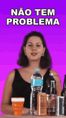 a woman is standing in front of a table full of bottles and cans with the words nao tem problema above her