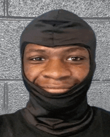 a man wearing a black mask looks at the camera