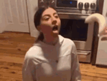 a woman is standing in front of a stove in a kitchen holding a piece of dough in her mouth .