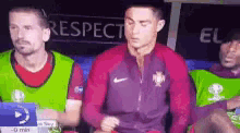 a group of soccer players are sitting in a locker room with a sign that says respect in the background .