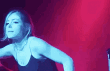 a woman is dancing on a stage in front of a red and blue light .