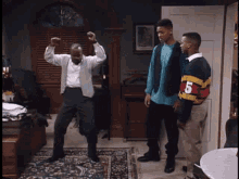 a man is dancing in a living room with two other men standing behind him .