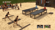 a group of people are playing a game on a sandy beach with a sign that says " survivor gr "