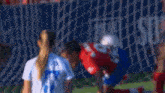 a group of women are playing soccer on a field and one of them is wearing a red and white striped shirt .