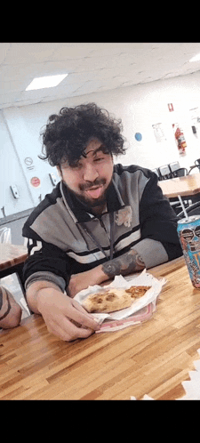 a man is sitting at a table with a slice of pizza and a can of dr pepper