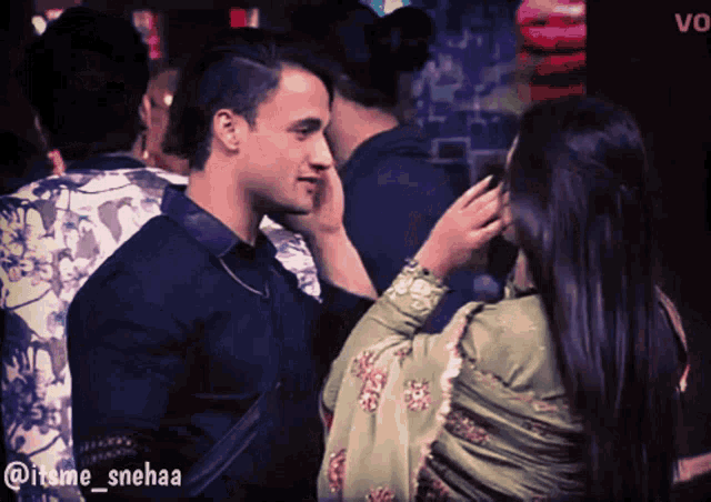 a woman touches a man 's face in a crowd with a caption that says @iteme_snehaa