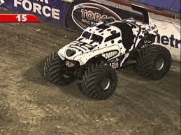 a white and black monster truck is driving down a dirt road .