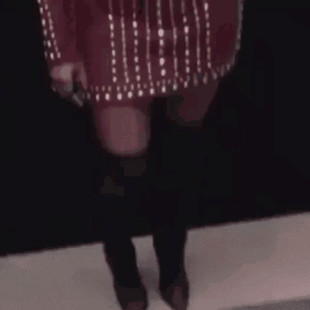 a woman in a red dress and black boots is standing on a stage in front of a black wall .