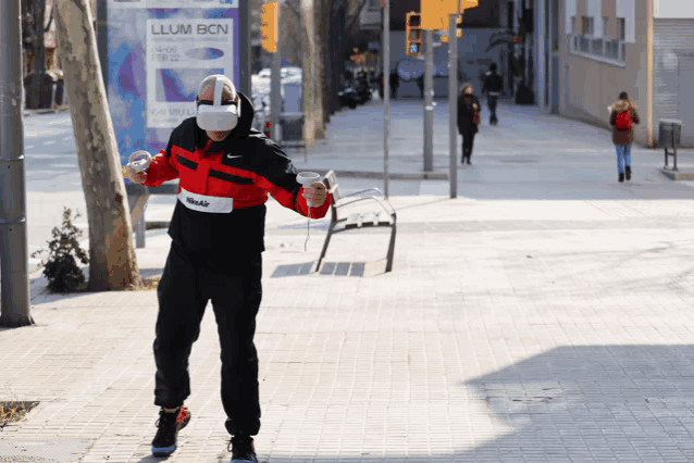 a man wearing a virtual reality headset stands in front of a billboard that says llum bcn