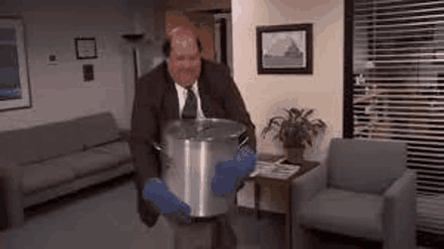 a man in a suit and tie is holding a large pot in his hands .