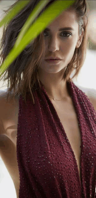 a close up of a woman 's face behind a palm tree leaf