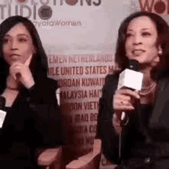 two women are sitting next to each other holding microphones .