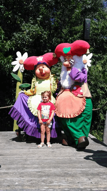 a little girl poses for a picture with a couple of cartoon characters