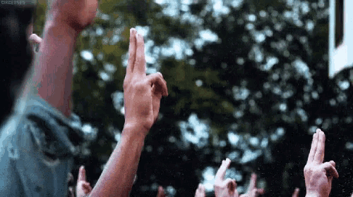 a man with a very long neck is giving a thumbs up sign in front of a crowd of people .