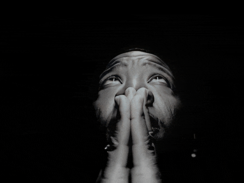 a black and white photo of a man with his hands folded in prayer