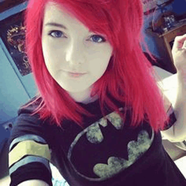 a girl with red hair is wearing a black batman shirt .