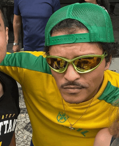 a man wearing green sunglasses and a yellow shirt with a soccer ball on it