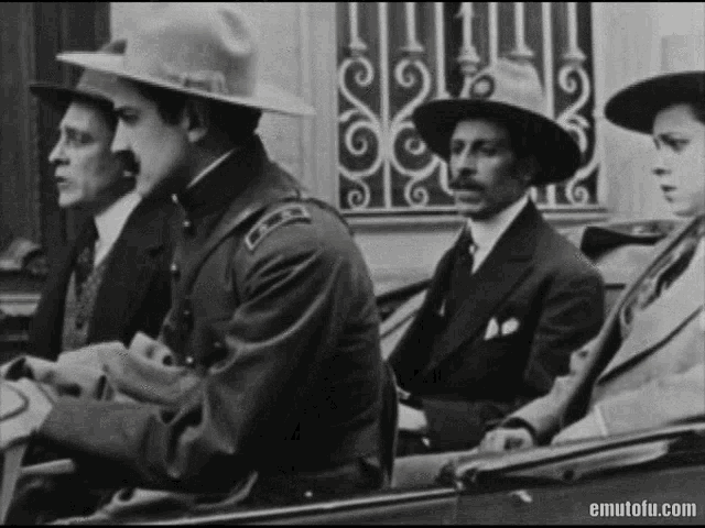 a group of men in suits and hats are sitting in a car in a black and white photo .