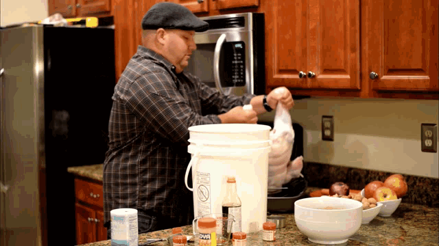 a man in a plaid shirt is preparing food in a kitchen with a bucket that says ' coca cola ' on it