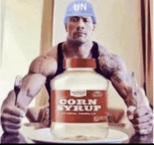 a muscular man is holding a fork and a bottle of corn syrup