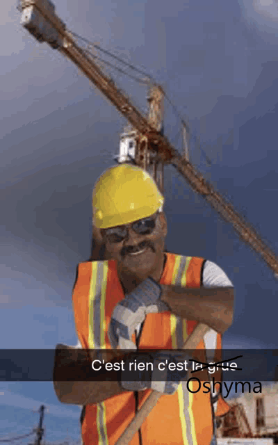 a construction worker wearing a hard hat and safety vest is standing in front of a crane