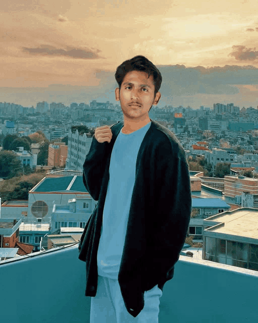 a man in a blue shirt and black jacket stands in front of a cityscape