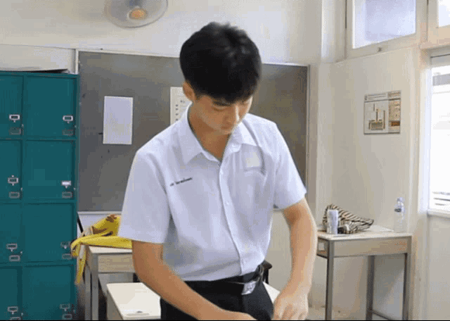 a boy in a white shirt with a name tag that says ' a ' on it is standing in a classroom