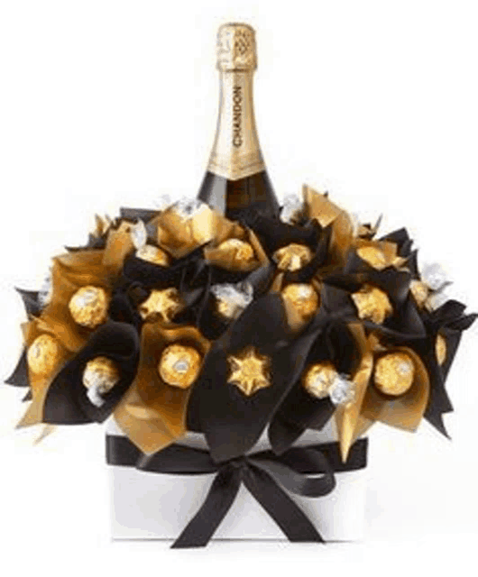 a bottle of champagne is sitting on top of a box filled with chocolates .