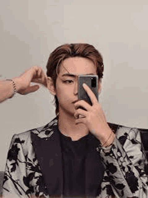 a man in a suit is taking a picture of himself in the mirror with his phone .