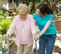 a woman in a blue shirt is helping an elderly woman with a walker