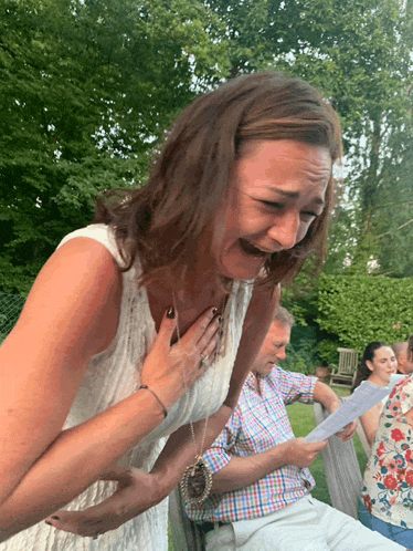 a woman in a white dress holds her hands to her chest