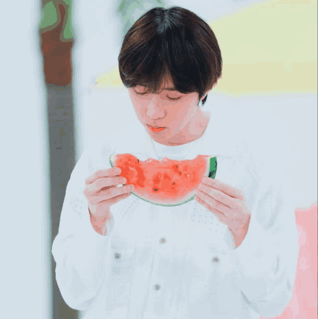 a young boy is eating a slice of watermelon