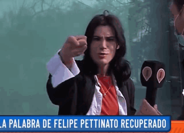 a woman in a red shirt holds a microphone in front of a sign that says la palabra de felipe