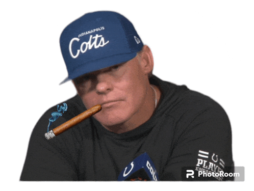 a man wearing a hat that says indianapolis colts is smoking a cigar