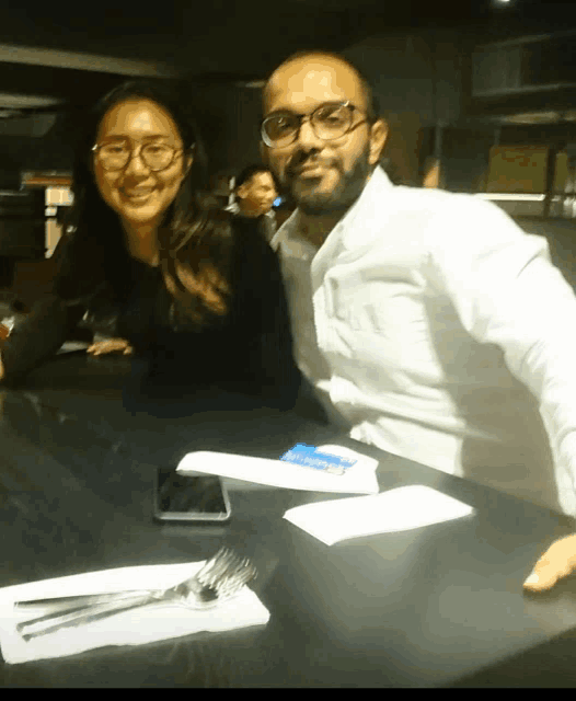 a man and a woman are posing for a picture at a restaurant table