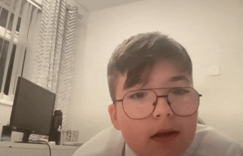 a boy wearing glasses is sitting in front of a dell computer monitor