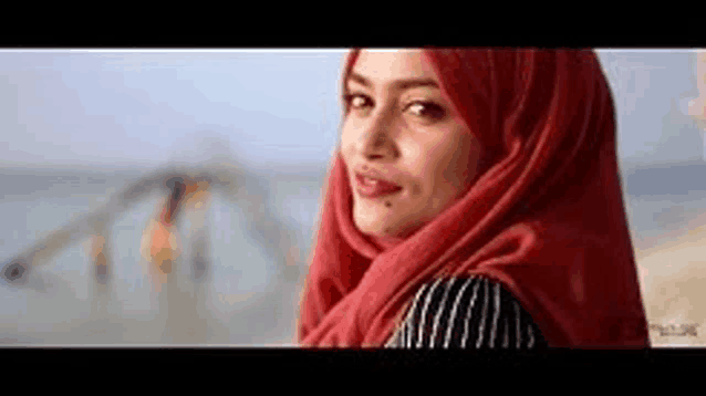 a woman wearing a red scarf is standing on a beach .