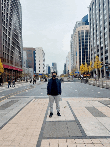 a man wearing a face mask stands in an empty city street