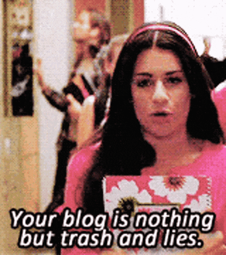 a woman in a pink shirt is holding a book and says your blog is nothing but trash and lies