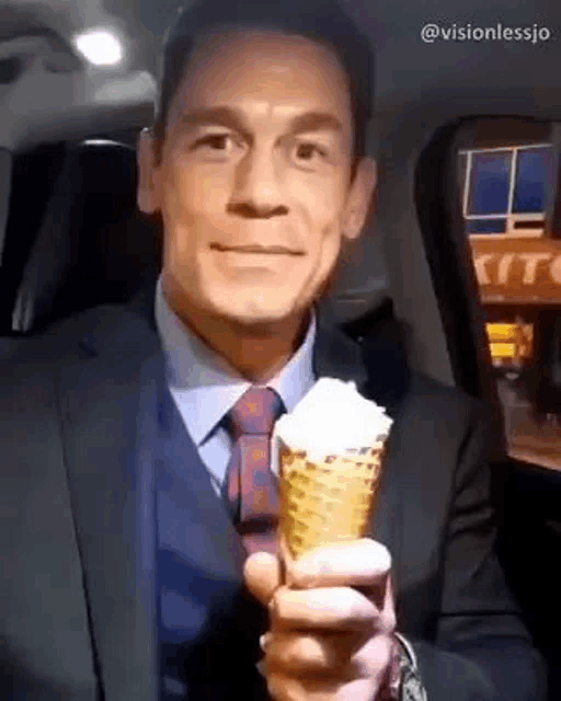 a man in a suit and tie is holding a cone of ice cream in his hand .