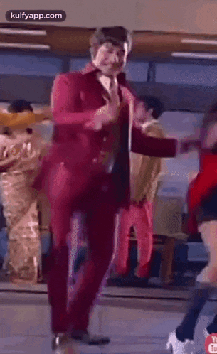 a man in a red suit is dancing with a woman in a red jacket .